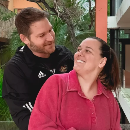 A happy, confident couple smiling at each other, showcasing natural-looking dental implant results at Smile Makeover Playa del Carmen