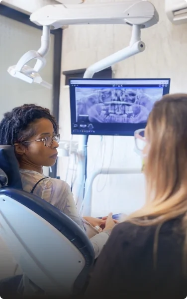 Dentist and patient discussing a 3D CBCT scan to create a personalized dental treatment plan.