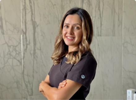 Dr. Dulce, an implantology specialist, smiling with arms crossed in professional black scrubs at Smile Makeover clinic