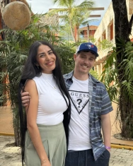 Happy couple smiling together against a tropical background after their dental treatment.
