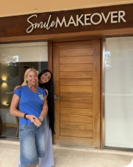 Smiling patients posing confidently in front of the Smile Makeover clinic entrance in Playa del Carmen.