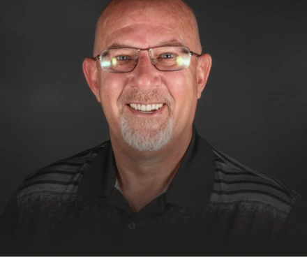Portrait of a confident, smiling man with glasses showcasing his results from Dental Implants.