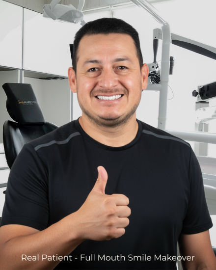 Male patient smiling after a complete smile makeover with crowns and veneers at a dental clinic.