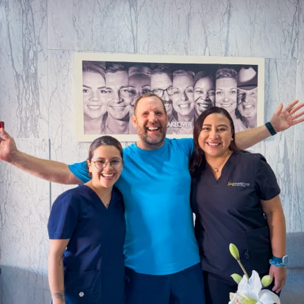 Happy patient with Smile Makeover dental team after successful 3 on 6 implant treatment.